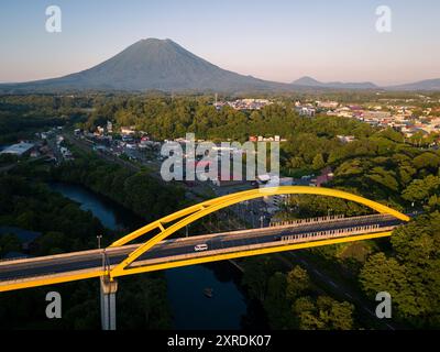 Niseko, Japan: Drohnenblick über die Brücke über den Shiribetsu-Fluss mit dem berühmten Berg Yotei im Hintergrund in Hokkaido im Sommer. Stockfoto