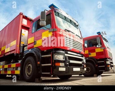 Zwei rote Feuerwehrfahrzeuge. Die Löschfahrzeuge sind mit Leitern, Löschgeräten und Wasser ausgestattet, um Leben zu retten und Gebäudebrände zu löschen. Stockfoto