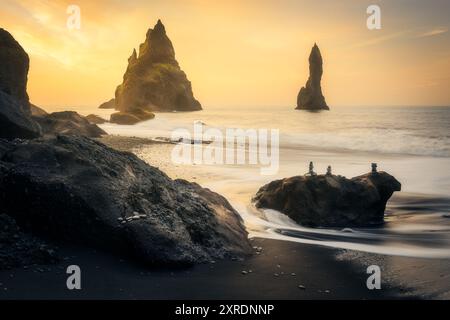 Wunderschöner Sonnenaufgang am schwarzen Sandstrand von Reynisfjara in Island, in der Nähe von Vik mit Steinchen Stockfoto