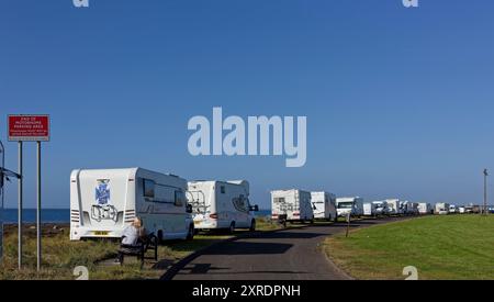 Eine Reihe von Wohnmobilen, die illegal am Rande des Strandes im inchcape Park in Arbroath geparkt wurden, hinter dem roten Schild, auf dem steht "kein Wohnmobil beyon" Stockfoto