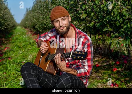 Der Mann spielt Gitarre. Naturhintergrund. Akustische Gitarren. Männlicher Musiker, der Gitarre spielt, Musikinstrument. Die Hände des Mannes spielen Akustikgitarre. Die Stockfoto