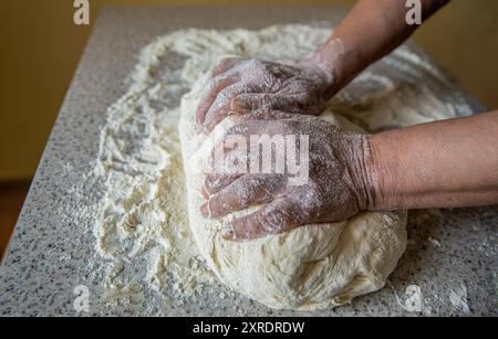 Zubereitungsteige. Die Zubereitung tränkt die Hände der Frauen. Teig mit männlichen Händen in der Bäckerei machen. Hände Teig. Weibliche Hände machen Teig für Pizza. Koch in Stockfoto