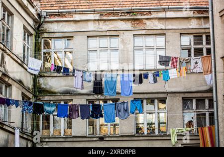 Kleidung wird an einem Seil zwischen Wissen getrocknet. Schlechter Bezirk. Gewaschene Kleidung, die vor einem alten Haus trocknet. Armer Bezirk, Häuser eines armen Bezirks Stockfoto