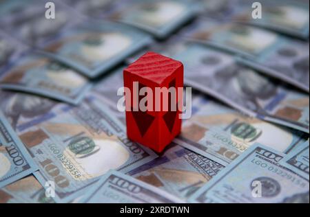 Ein roter Pfeil, der nach unten zeigt, auf einem Stapel US-Dollar-Scheine. Wirtschaftliche Rezession, finanzieller Rückgang, Konzept des wirtschaftlichen Abschwungs. Stockfoto