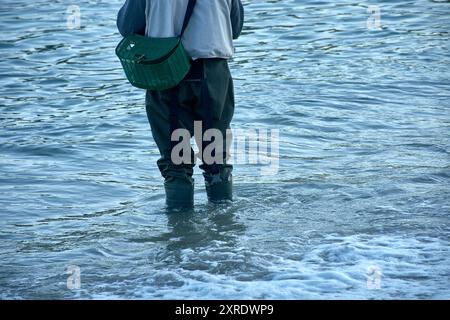 Die traditionelle Kleidung eines Fischers, der im Wasser watet, ausgestattet mit robusten Stiefeln und einem Korb für den Fang. Die Stiefel sind so konzipiert, dass sie Stockfoto