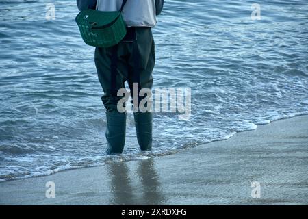 Die traditionelle Kleidung eines Fischers, der im Wasser watet, ausgestattet mit robusten Stiefeln und einem Korb für den Fang. Die Stiefel sind so konzipiert, dass sie Stockfoto