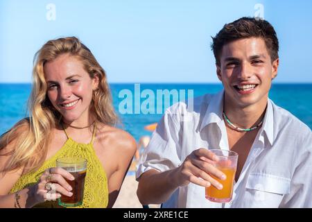 Glückliches junges Paar im Urlaub, trinkt im Restaurant und blickt in die Kamera Stockfoto