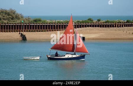 Vintage-Yacht mit rotem Segel, die in die Flussmündung des Deben bei Felixstowe Ferry eindringt. Stockfoto