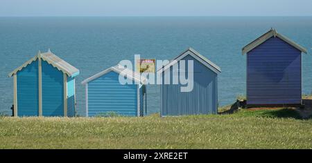 Strandhütten in einer Reihe Meer im Hintergrund 1 Hütte mit zum Verkauf Board. Stockfoto