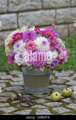 Romantischer Blumenstrauß mit violetten und weißen Dahlien, Zinnien, Nelken und wilden Karotten in einem Vintage Blumentopf im Garten Stockfoto