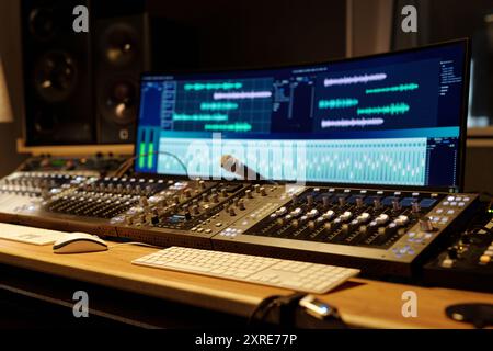 Audio-Mischen und -Aufnahme erfolgt mit High-End-Studioausrüstung mit mehreren Bildschirmen und Mischkonsolen in einem gut beleuchteten professionellen Aufnahmestudio Stockfoto