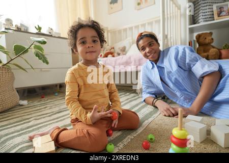 Lächelnde Mutter spielt mit Kind im gemütlichen Spielzimmer Stockfoto