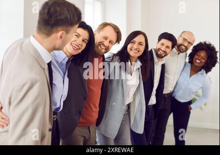 Fröhliche Geschäfte, multiethnische Menschen, Männer und Frauen, die in einer Reihe im Büro stehen und lächeln. Stockfoto