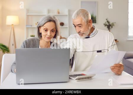 Reife Ehepaare haben sich mit moderner Technologie in die Verwaltung ihres Haushaltsbudgets eingelassen. Stockfoto