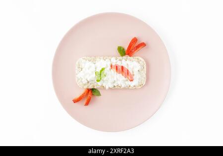 Länglicher Reiskuchen mit Hüttenkäse und Erdbeeren auf rosafarbenem Teller Stockfoto