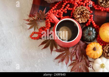 Herbststillleben mit Kaffeetasse, roter Kerze und dekorativen Kürbissen auf einem Tisch. Gemütliches Herbstkonzept. Stockfoto