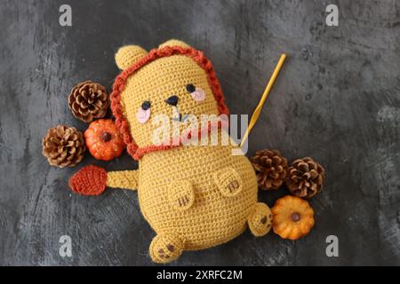 Kuschelspielzeug mit gehäkeltem Löwen aus nächster Nähe. Niedliche handgemachte Teppichpuppe auf dunklem strukturiertem Hintergrund mit Kopierraum. Stockfoto