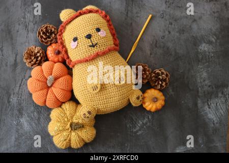 Kuschelspielzeug mit gehäkeltem Löwen aus nächster Nähe. Niedliche handgemachte Teppichpuppe auf dunklem strukturiertem Hintergrund mit Kopierraum. Stockfoto