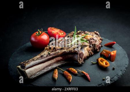 Köstliches Rindersteak mit Rosmarin, Chili Peeper und Tomaten auf Schieferbrett. Geröstetes Ribeye-Rindersteak mit Kräutern und Gemüse Stockfoto