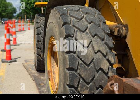 Große Räder an einem Frontlader, die bei einem Straßenbauprojekt im Leerlauf sitzen, werden aus nächster Nähe gesehen und betonen ihre Größe und Leistung. Stockfoto