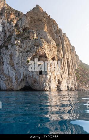 Blaues Wasser vor einer Klippe in Masua, auf Sardinien mit verlassener Mine Porto Flavia in der Mitte der Mauer. Ein altes und verlassenes Zink-Min Stockfoto