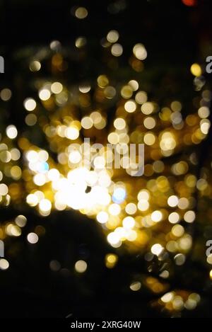 Ein defokussiertes Foto einer festlichen Dekoration auf einem Weihnachtsbaum: Ein Haufen goldener Lichter auf dunklem Hintergrund. Weihnachtlicher Hintergrund aus Sarajevo Stockfoto