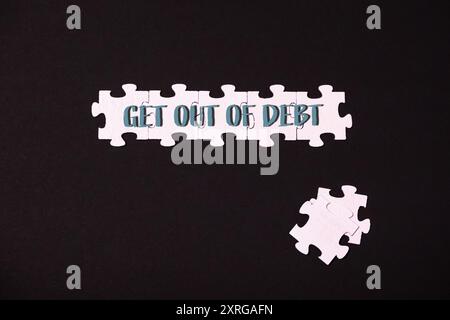 Ein Puzzleteil mit den Worten „Get out of Debt“, das die Herausforderung und das Ziel der Erlangung finanzieller Freiheit symbolisiert. Stockfoto