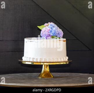 Schöner weißer Geburtstagskuchen mit frischen Blumen vor einem Hintergrund Stockfoto