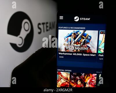 Person, die ein Smartphone hält, mit der Webseite des US-amerikanischen Videospielvertriebs Steam (Valve) vor dem Logo. Konzentrieren Sie sich auf die Mitte des Telefondisplays. Stockfoto