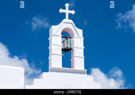Alte Glocke auf einer weißen christlichen Kirche unter blauem Himmel Stockfoto