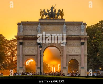 Paris, Frankreich - 08 05 2024: Olympische Spiele Paris 2024. Blick auf den Olympischen Kessel hinter dem Triumphbogen am Carrousel du Louvre bei Nacht Stockfoto