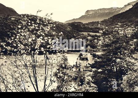 Schöner See von Annecy (bekannt als Europas sauberster See) mit der Burg durch die Kiefern und Dorfhäuser auf der anderen Seite des Sees. Haut Stockfoto