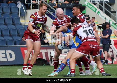 Leeds, Großbritannien. August 2024. AMT Headingley Rugby Stadium, Leeds, West Yorkshire, 10. August 2024. Betfred Super League Leeds Rhinos gegen Wigan Warriors Tom Nicholson-Watton von Leeds Rhinos wird von Liam Farrell, Patrick Mago und Liam Byrne von Wigan Warriors angegriffen Stockfoto