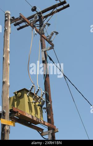 Stromtransformator auf Holzmasten, alte elektrische Infrastruktur Stockfoto