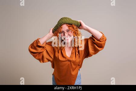 Porträt einer lächelnden, schönen jungen Frau, die einen Strickmütze trägt und fröhlich auf dem Hintergrund posiert Stockfoto