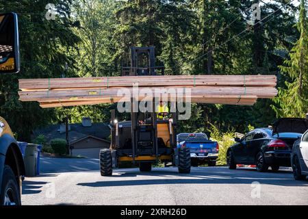 BELLEVUE, WA – 25. JUN 2024: Mann, der Gabelstapler auf Wohnstraßen fährt und Baumaterialien und lange Holzbretter transportiert Stockfoto