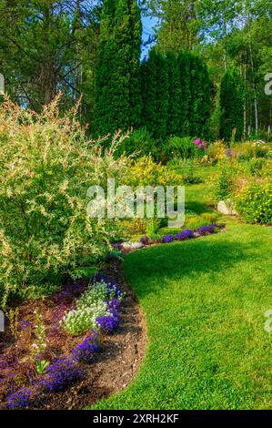 Ein wunderschön gestalteter Garten mit einer Fülle von Blumen und farbenfrohen Pflanzen Stockfoto