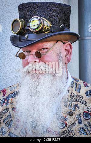 Henrichenburg, Waltrop, Deutschland. August 2024. Ein viktorianischer Biker mit Top-Hut. Steampunk-Fans, Gruppen und Besucher, viele davon in Retro-futuristischen oder viktorianischen Kostümen, haben am ersten Tag des jährlichen Steampunk Jubilee Festivals und Markts Spaß. In diesem Jahr fällt das Festival mit dem 125-jährigen Jubiläum der historischen Henrichenburger Bootsliftanlage zusammen, einem denkmalgeschützten Industriedenkmal entlang des Dortmund-Ems-Kanals. Quelle: Imageplotter/Alamy Live News Stockfoto