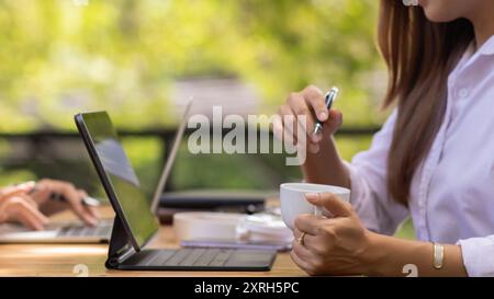 Junge Geschäftsfrau prüft die Ergebnisse des Unternehmensnetzwerks über Laptops und das Internet, um Dokumente für Treffen vorzubereiten, die Investoren zur Verfügung gestellt werden können Stockfoto