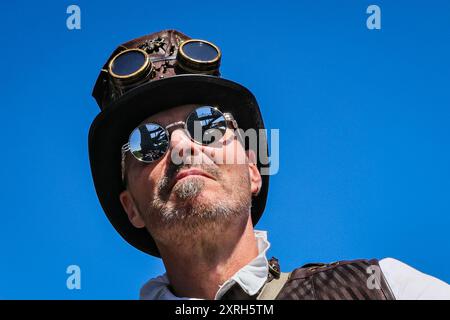 Henrichenburg, Waltrop, Deutschland. August 2024. Der historische Bootslift spiegelt sich in der Brille eines Teilnehmers wider. Steampunk-Fans, Gruppen und Besucher, viele davon in Retro-futuristischen oder viktorianischen Kostümen, haben am ersten Tag des jährlichen Steampunk Jubilee Festivals und Markts Spaß. In diesem Jahr fällt das Festival mit dem 125-jährigen Jubiläum der historischen Henrichenburger Bootsliftanlage zusammen, einem denkmalgeschützten Industriedenkmal entlang des Dortmund-Ems-Kanals. Quelle: Imageplotter/Alamy Live News Stockfoto