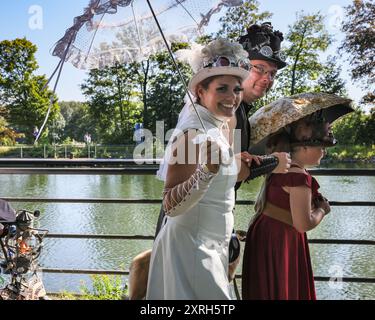 Henrichenburg, Waltrop, Deutschland. August 2024. Die Teilnehmer spazieren entlang des Kanals bei schönem Sonnenschein. Steampunk-Fans, Gruppen und Besucher, viele davon in Retro-futuristischen oder viktorianischen Kostümen, haben am ersten Tag des jährlichen Steampunk Jubilee Festivals und Markts Spaß. In diesem Jahr fällt das Festival mit dem 125-jährigen Jubiläum der historischen Henrichenburger Bootsliftanlage zusammen, einem denkmalgeschützten Industriedenkmal entlang des Dortmund-Ems-Kanals. Quelle: Imageplotter/Alamy Live News Stockfoto