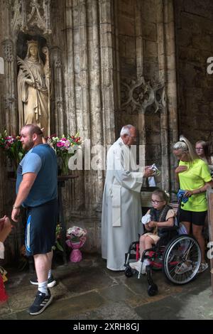 St. Winefrides Schrein. Katholische Pilger am Festtag von Saint Winefride verehren St. Winefride Relic. Eine Mutter bringt ihre behinderte Tochter mit, die im Rollstuhl sitzt. Sie verehrt das Relikt und betet. Ein katholischer Mann berührt die Statue von St. Winefride. Holywell Flintshire Wales Juni 2023. HOMER SYKES AUS DEN 2000ER JAHREN Stockfoto