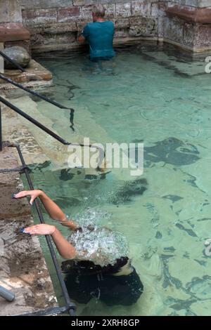 St. Winefrids-Schrein und heiliger Brunnen. Katholische Wallfahrt am 22. Juni zum Festtag des Heiligen Winefride. Im äußeren Becken kniet eine junge Frau auf einem untergetauchten Stein, der als St. Beuno-Stein bekannt ist, so lange es dauert, das Rosenkranzgebet zu vollenden. Ich bin dreimal um den äußeren Pool gelaufen, in der Hoffnung auf ein Wundermittel. Holywell, Flintshire Wales, UK 1990s. HOMER SYKES Stockfoto