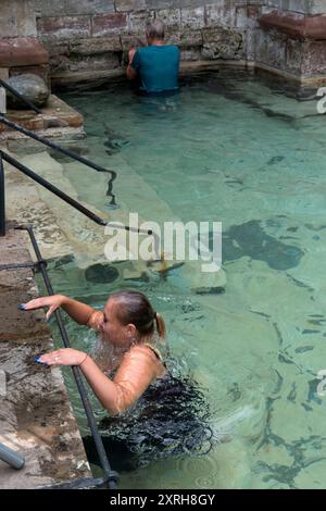 St. Winefrids-Schrein und heiliger Brunnen. Katholische Wallfahrt am 22. Juni zum Festtag des Heiligen Winefride. Im äußeren Becken kniet eine junge Frau auf einem untergetauchten Stein, der als St. Beuno-Stein bekannt ist, so lange es dauert, das Rosenkranzgebet zu vollenden. Ich bin dreimal um den äußeren Pool gelaufen, in der Hoffnung auf ein Wundermittel. Holywell, Flintshire Wales, UK 1990s. HOMER SYKES Stockfoto