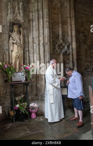 St. Winefrids-Schrein und heiliger Brunnen. Holywell Flintshire. Katholische Wallfahrt am Festtag des Heiligen Winefride. Der Priester hält das St. Winefrids Relic zur Verehrung aus. Ein Pilger sagt ein Gebet. Wales Juni 2023. HOMER SYKES AUS DEN 2000ER JAHREN Stockfoto