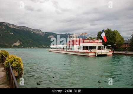 Annecy Lake, Frankreich - 24. August 2015: Restaurantschiff mit französischer Flagge bei Sonnenuntergang. Die Annecy Lake Boat Company bietet geführte Bootstouren an Stockfoto