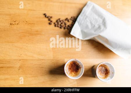 Zwei Tassen Cappuccino mit einer Tüte Kaffeebohnen auf einem Holztisch Stockfoto
