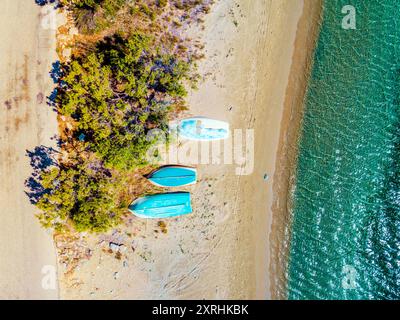 Drei kleine Ruderboote liegen kopfüber an einem Strand am Meer, Paros, Griechenland Stockfoto