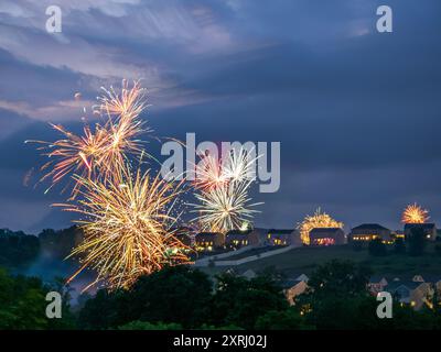 Ein schillerndes Feuerwerk beleuchtet den Nachthimmel im Sommer, der vor Farben und Licht über einem ruhigen Wohngebiet in den USA strotzt und den Himmel fängt Stockfoto