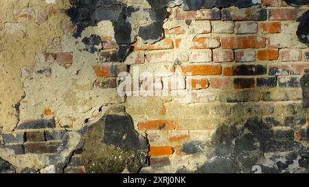 Nahaufnahme einer verwitterten Ziegelwand mit Rissen und unterschiedlichen Farbtönen. Stockfoto